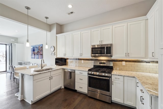 kitchen featuring a sink, a peninsula, stainless steel appliances, visible vents, and white cabinetry