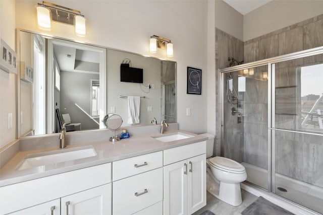 bathroom with a sink, double vanity, toilet, and a stall shower