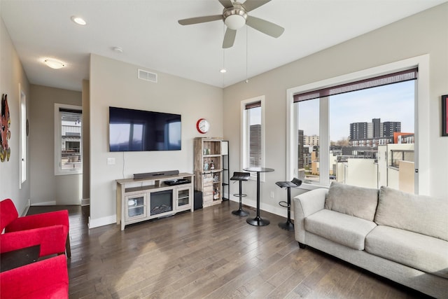 living area with visible vents, baseboards, a healthy amount of sunlight, and dark wood-style floors