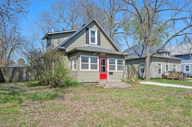 bungalow featuring a front lawn, a chimney, fence, and a deck