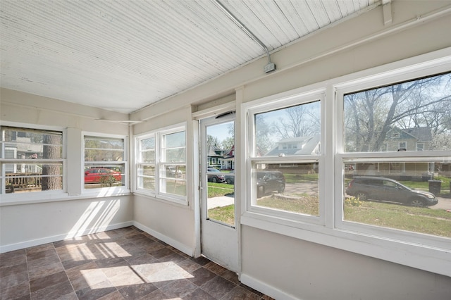 unfurnished sunroom featuring baseboards and stone finish flooring