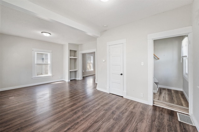 unfurnished living room with a wealth of natural light, stairway, baseboards, and dark wood-style floors