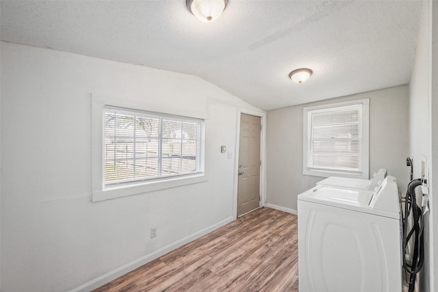 laundry area featuring a textured ceiling, baseboards, washing machine and clothes dryer, light wood-style floors, and laundry area