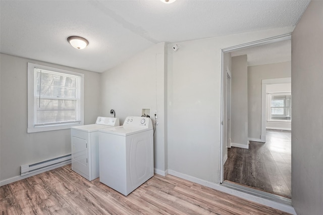 clothes washing area with a baseboard radiator, washing machine and dryer, a textured ceiling, laundry area, and light wood-type flooring