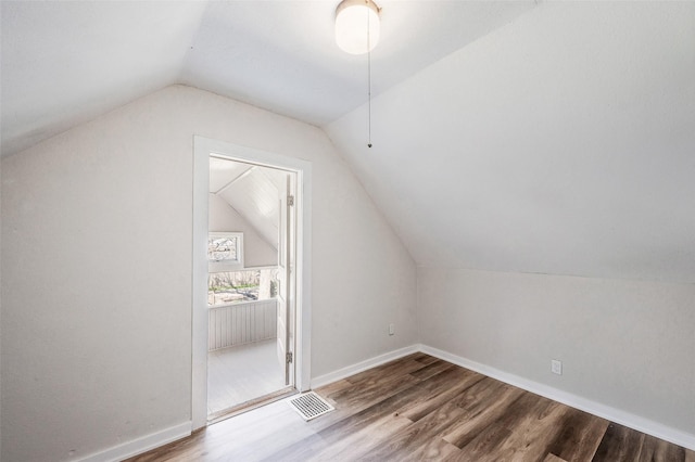 additional living space with vaulted ceiling, baseboards, visible vents, and wood finished floors