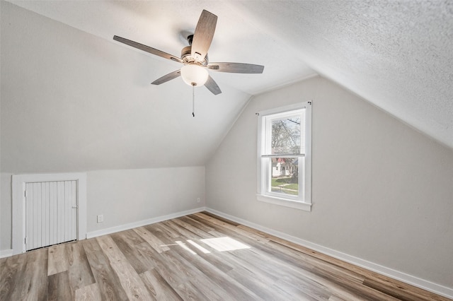 additional living space with lofted ceiling, baseboards, light wood finished floors, and ceiling fan