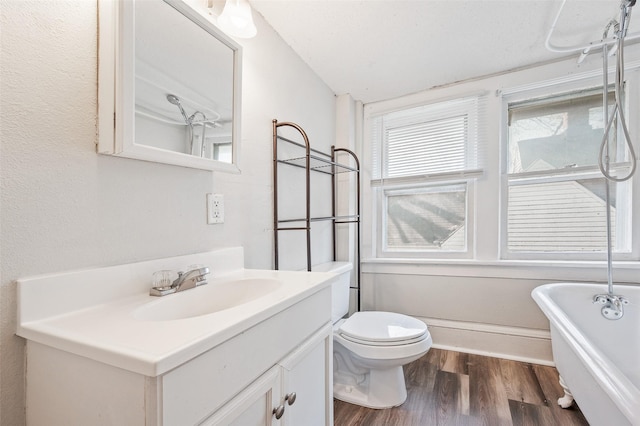 full bath with vanity, a soaking tub, toilet, and wood finished floors
