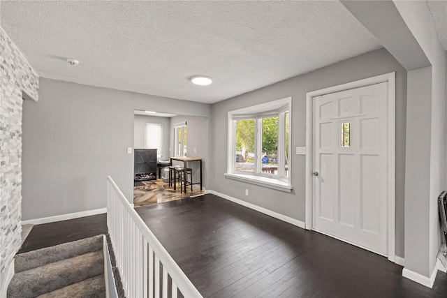 foyer featuring baseboards, dark wood-style flooring, and a textured ceiling