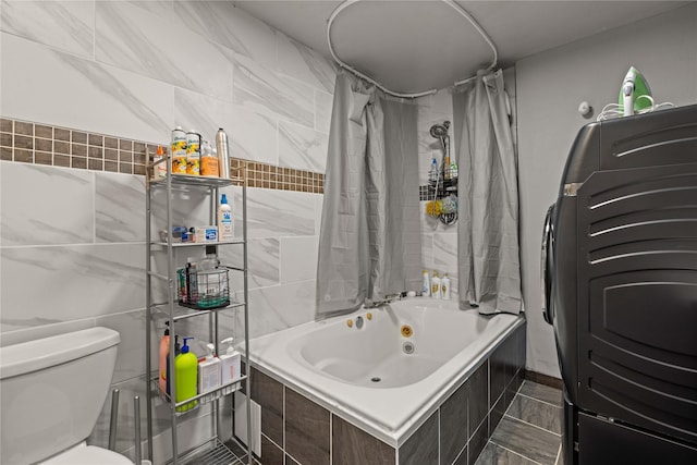 full bath featuring a combined bath / shower with jetted tub, washer / clothes dryer, toilet, and tile walls