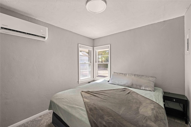 carpeted bedroom featuring baseboards, a wall mounted AC, and a textured wall
