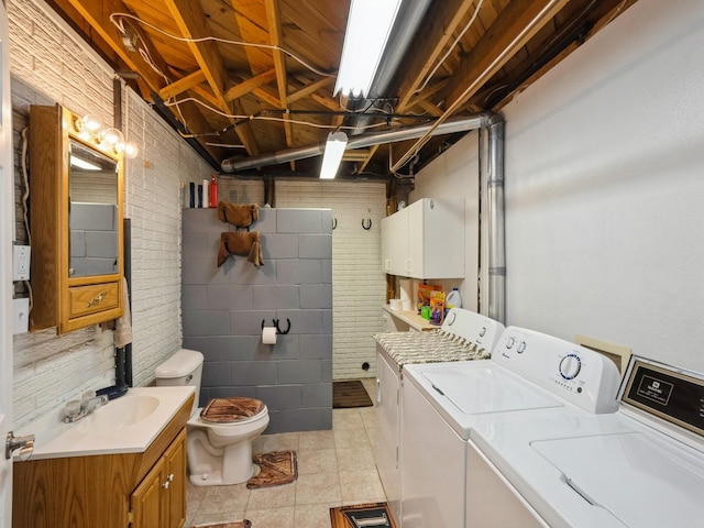 interior space with washing machine and clothes dryer, brick wall, laundry area, and light tile patterned floors