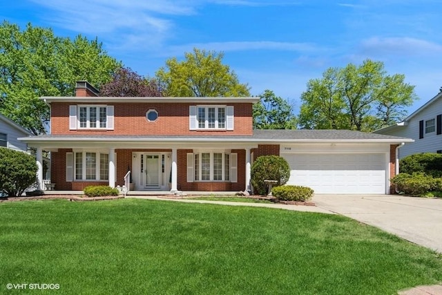 traditional-style home with concrete driveway, a front yard, brick siding, and an attached garage