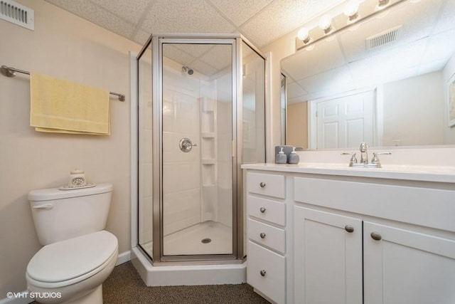 full bathroom with toilet, vanity, visible vents, a shower stall, and a paneled ceiling