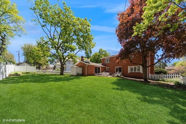 view of yard with an outdoor structure, a fenced backyard, and a storage unit