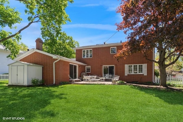 rear view of property featuring a storage shed, a patio, a chimney, a lawn, and brick siding