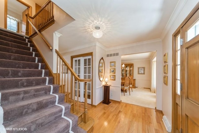 foyer entrance featuring light wood finished floors, stairs, plenty of natural light, and visible vents