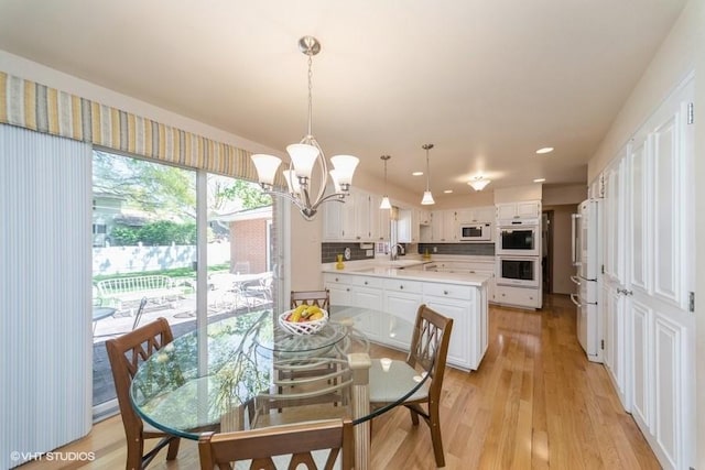 dining room with a notable chandelier, light wood-type flooring, and recessed lighting