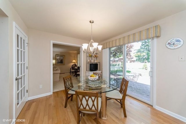 dining area with baseboards, light wood finished floors, and a chandelier