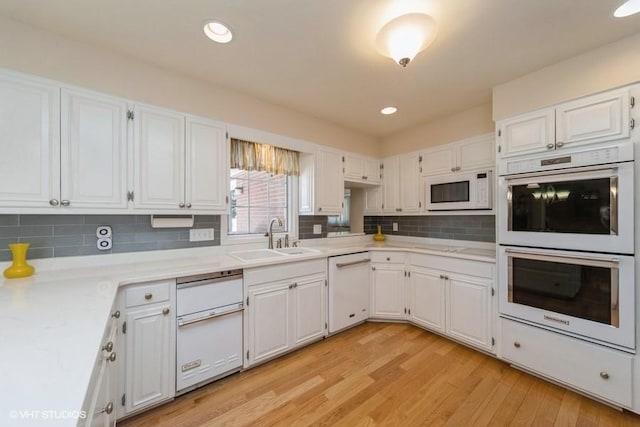 kitchen with white appliances, white cabinets, and a sink
