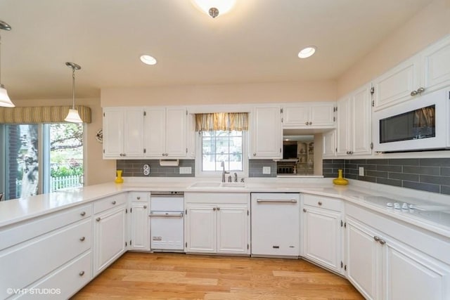 kitchen with white cabinets, a healthy amount of sunlight, a sink, and white appliances