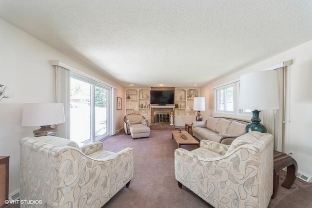 living room featuring a textured ceiling, a fireplace, visible vents, and carpet