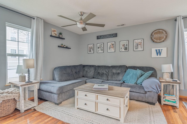 living area with light wood-style floors, visible vents, and a ceiling fan
