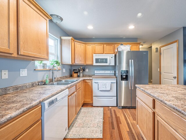 kitchen featuring light wood finished floors, recessed lighting, a sink, and white appliances
