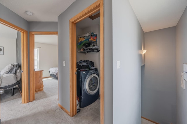 hallway featuring light carpet and washer / dryer