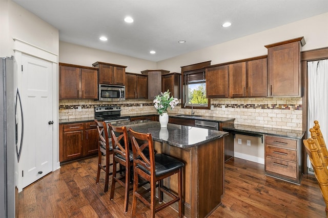 3414 163rd St, Urbandale, IA 50323 - kitchen featuring stainless steel appliances, dark wood-style floors, a sink, a kitchen island, and decorative backsplash