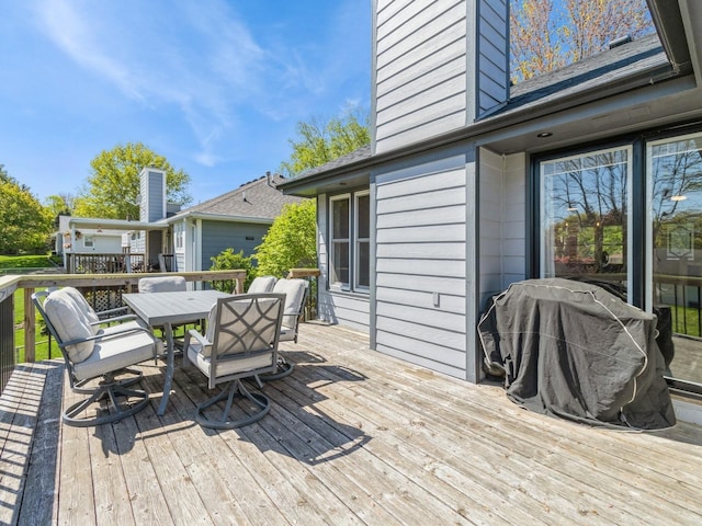 wooden terrace with outdoor dining space and grilling area