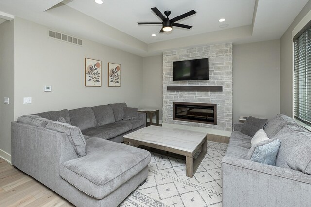 730 NE Country Meadow Dr, Ankeny, IA 50021 - living room featuring a tray ceiling, light wood-style floors, a ceiling fan, recessed lighting, and a fireplace