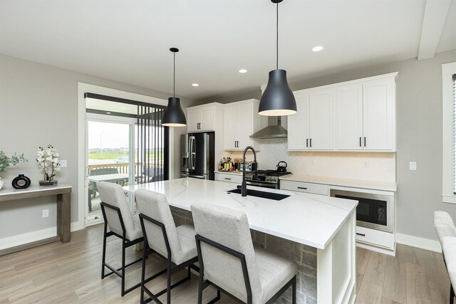 730 NE Country Meadow Dr, Ankeny, IA 50021 - kitchen with stainless steel appliances, wall chimney range hood, decorative backsplash, light wood finished floors, and an island with sink