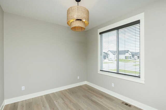 730 NE Country Meadow Dr, Ankeny, IA 50021 - spare room with baseboards, a chandelier, and light wood-type flooring