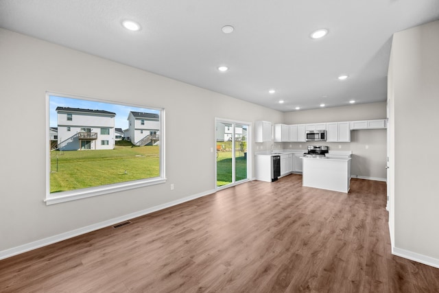 unfurnished living room featuring wood finished floors, baseboards, recessed lighting, and a sink