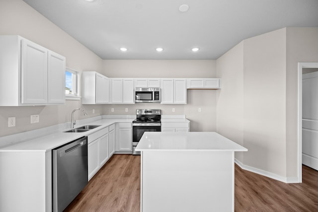 kitchen featuring stainless steel appliances, a sink, light wood-type flooring, recessed lighting, and white cabinetry