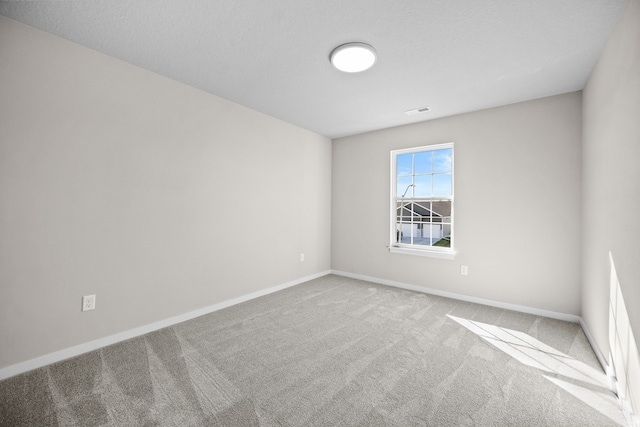 spare room featuring carpet and baseboards