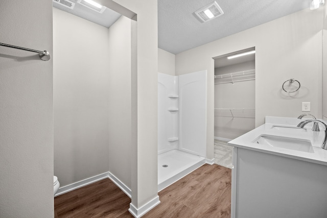 bathroom featuring wood finished floors, a shower, toilet, and baseboards