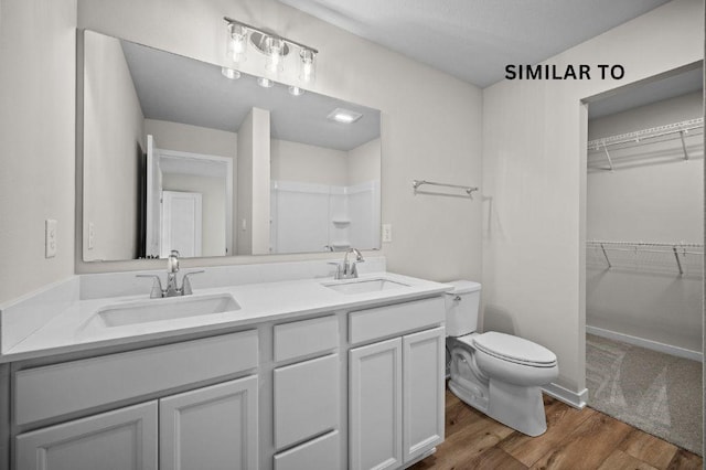 4404 Honey Bee Rdg, Des Moines, IA 50317 - bathroom featuring wood finished floors, toilet, double vanity, a walk in closet, and a shower