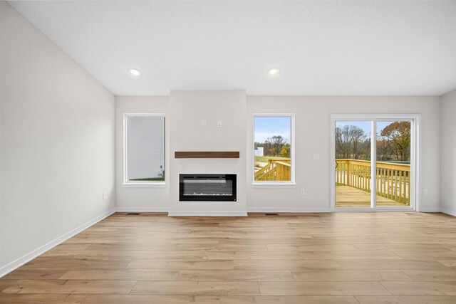 4408 Honey Bee Rdg, Des Moines, IA 50317 - unfurnished living room featuring light wood finished floors, a glass covered fireplace, and recessed lighting
