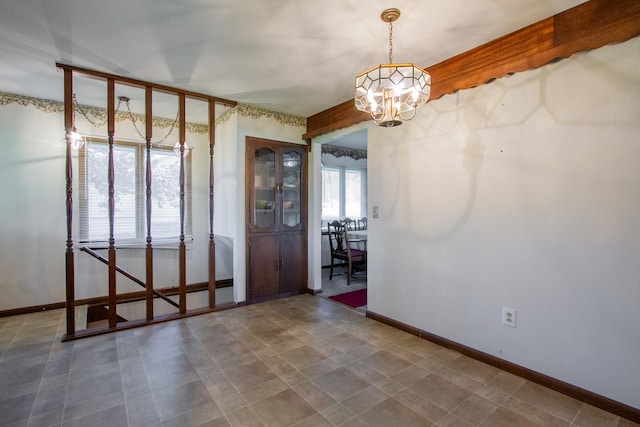 empty room with a chandelier and baseboards