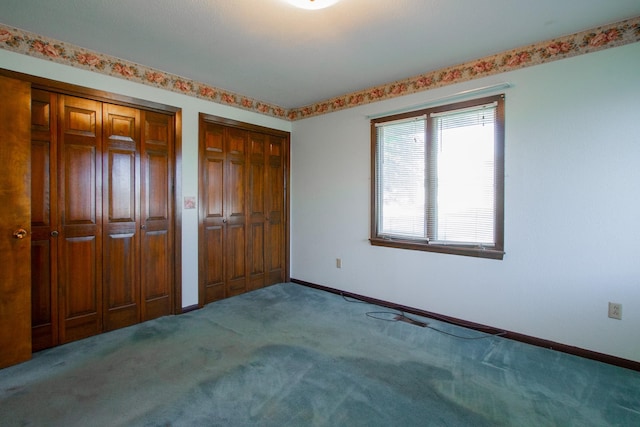 unfurnished bedroom with multiple closets, carpet flooring, and baseboards