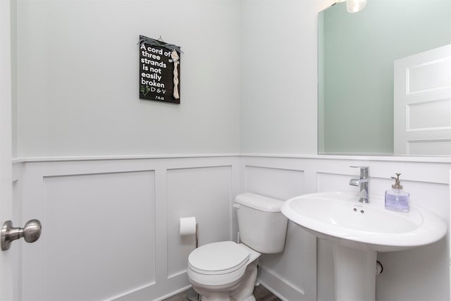 3316 NW 27th St, Ankeny, IA 50023 - bathroom featuring a decorative wall, toilet, wainscoting, and a sink