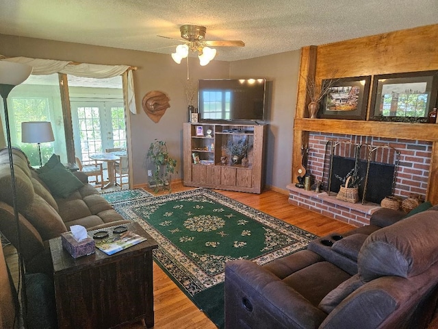 1991 190th Ave, Osceola, IA 50213 - living room featuring a ceiling fan, wood finished floors, a brick fireplace, a textured ceiling, and baseboards