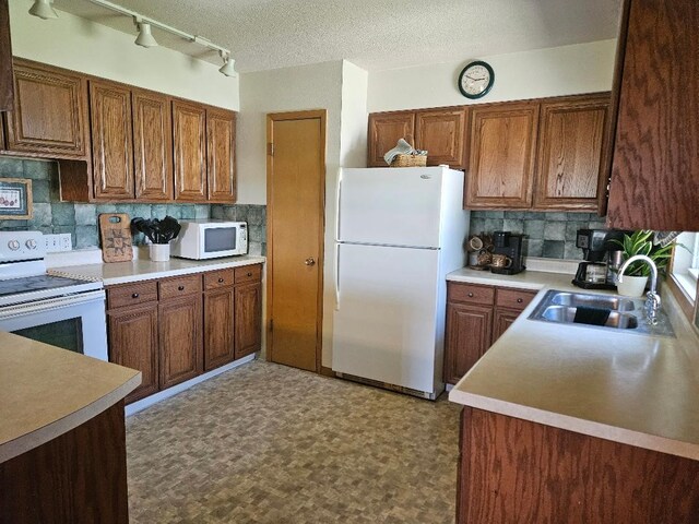 1991 190th Ave, Osceola, IA 50213 - kitchen with white appliances, a sink, tasteful backsplash, brown cabinetry, and light countertops