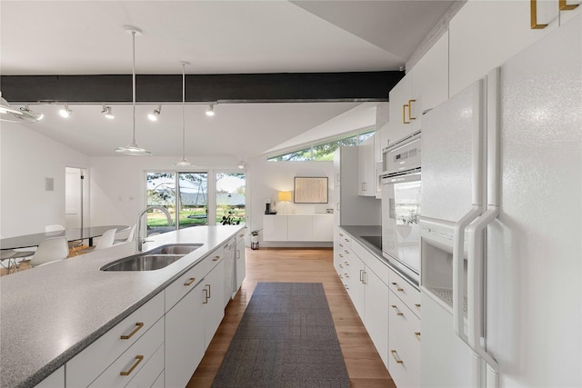 kitchen featuring white appliances, a sink, light wood-type flooring, white cabinets, and decorative light fixtures