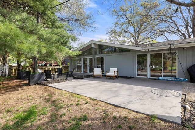 rear view of property featuring a patio, fence, and a sunroom