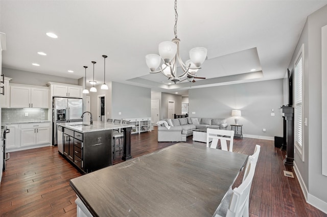 235 Emerson Ln, Waukee, IA 50263 - dining area with a chandelier, a tray ceiling, baseboards, dark wood-type flooring, and recessed lighting
