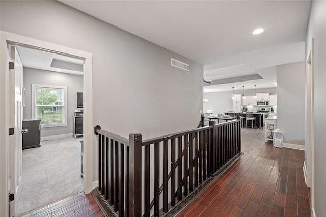 235 Emerson Ln, Waukee, IA 50263 - hallway with an upstairs landing, dark wood-type flooring, baseboards, recessed lighting, and a tray ceiling