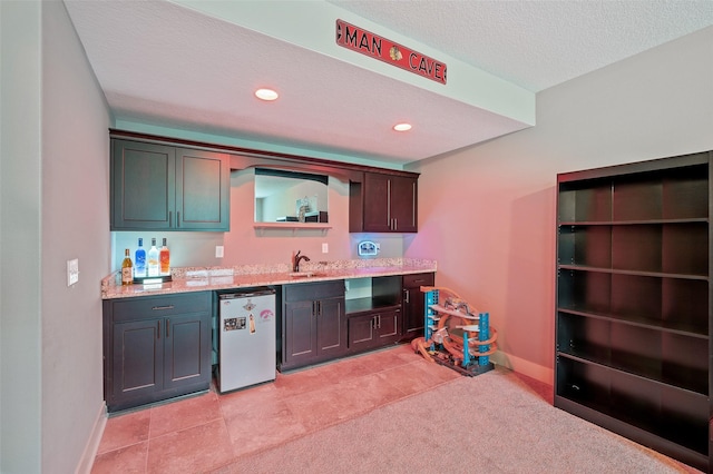 235 Emerson Ln, Waukee, IA 50263 - kitchen featuring refrigerator, baseboards, a sink, a textured ceiling, and recessed lighting