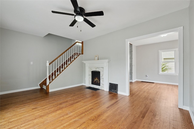 330 E 13th St N, Newton, IA 50208 - unfurnished living room featuring light wood-style floors, a fireplace, a ceiling fan, stairs, and baseboards